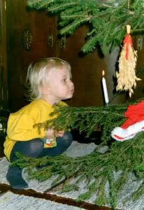 Pieni lapsi ihmettelee elävää kynttilää joulukuusessa.